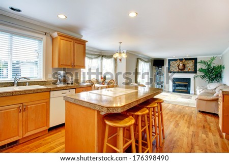 Bright kitchen room with counter stools and small dining area extended to cozy living room with fireplace and leather couch