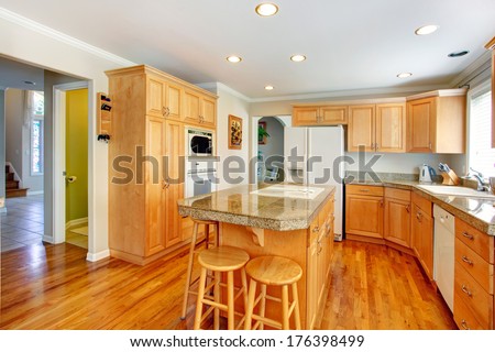 Light brown kitchen room with white appliances, counter and bar stools