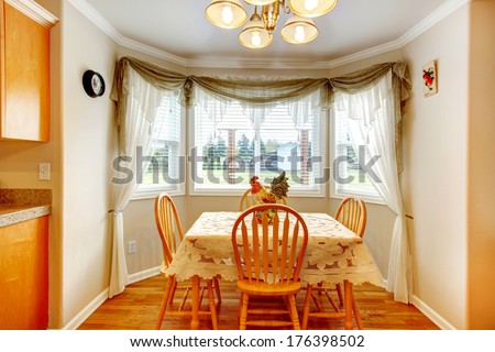 Small dining area with rounded corner, rustic wooden table set and decorative rooster on the table