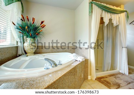Bright beautiful bathroom with concrete floor, open shower, whirpool. Decorated with antique vase and dry decorative sedge