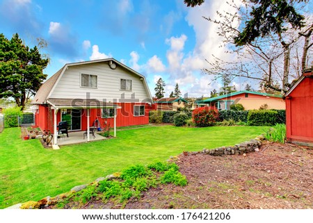 Beautiful green backyard with trimmed hedges, attached pergola with small patio area.