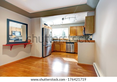 Small kitchen room with wooden storage cabinets, steel modern appliances. Open wall design with dining area.