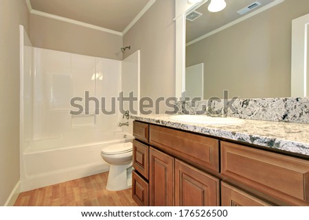 Soft colors bathroom with hardwood floor and wooden cabinets. White bath tub and toilet
