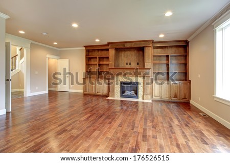 Bright Living Room With Hardwood Floor, Beige Wall, Wooden Storage Combination And Stone Background Fireplace