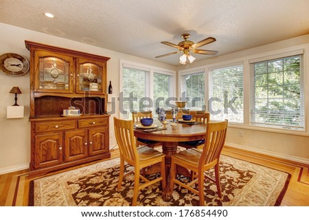 Bright dining room with rustic dining table set and wooden storage cabinet. Room has hardwood floor with soft brown and mocha rug