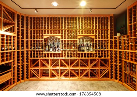 Bright home wine cellar with wooden storage units and arch with bottles.
