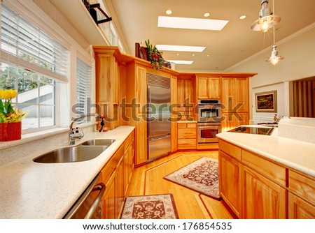 Bright Kitchen Room With Light Brown Storage Combination And White Counter Tops, Steel Appliances, Hardwood Floor And Rugs