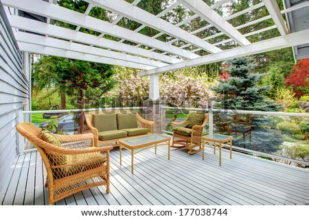 Cozy covered walkout deck with wicker and rocking chairs, settee, coffee table. Screened deck overlooking beautiful flourishing garden
