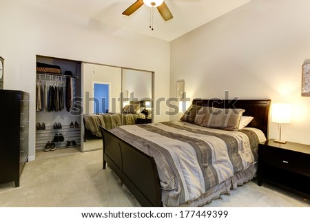 Elegant bedroom with dark brown furniture, mirror door closet