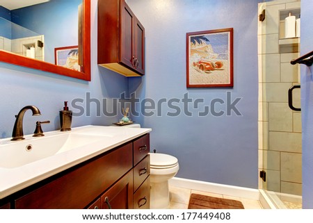 Contrast color bathroom with lavender wall and cherry color washbasin cabinet with white counter top