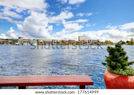 Beautiful view of Washington lake, forest, bridge and city landscape from boat house dock.  Wooden bench and red pot with small fir tree