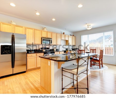 Large Kitchen Room With Hardwood Floor. Light Tones Storage Cabinets With Black Counter Tops