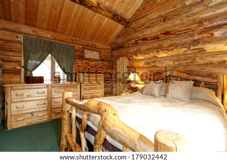 Warm cozy bedroom with rustic bed, nightstand and dresser. Green carpet floor and curtains. Log cabin house interior