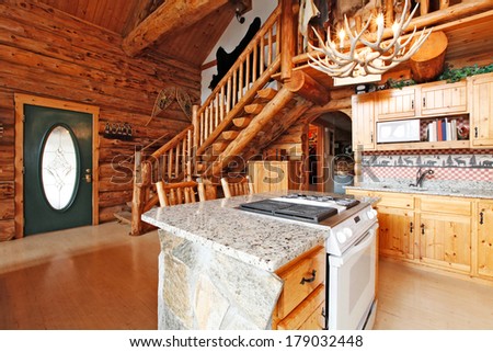 Log cabin house kitchen room with rocky cabinet and white stove. View of entrance hall and rustic stairs