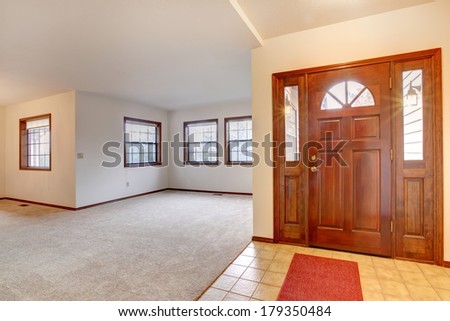 View of the empty living room from an entrance hallway with tile floor and rug