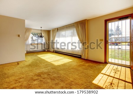 Empty bright room with one window, beige carpet floor.