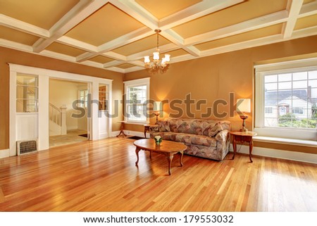 Living room with a coffered ceiling and hardwood floor. Furnished with an antique sofa, coffee table. View of the hallway