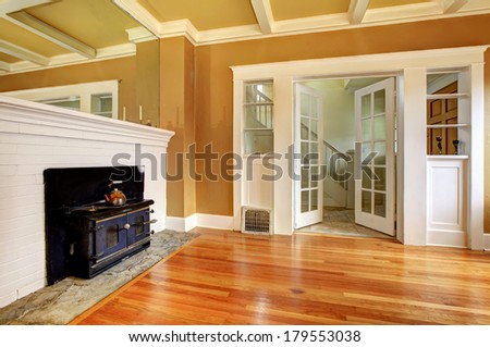 Mustard and white empty living room with a hardwood floor and antique black stove