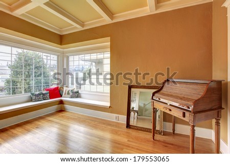 Empty room with a coffered ceiling, hardwood floor. Corner decorated with an antique chest and mirror