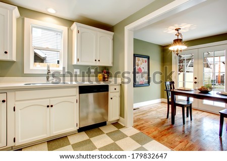 White kitchen cabinets blends perfectly with light olive walls, olive and beige ceramic tile floor. View of the dining room