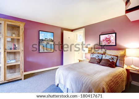 Elegant bedroom with beige carpet floor and contrast color bright red walls. Green and purple bedding blend perfectly with red wall