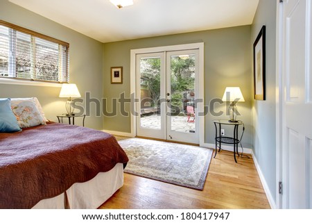 Olive walls cozy bedroom with hardwood floor and glass doors. View of the walkout deck