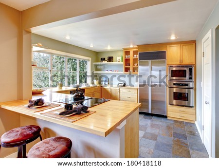 Kitchen with maple cabinets and steel appliances. View of the kitchen and counter top with stools from a dining area