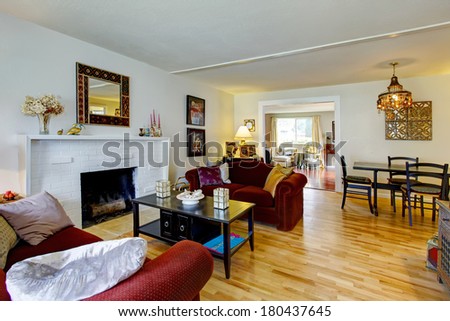 White living room with a brick background fireplace, black coffee table and burgundy love seats. View of the dining area