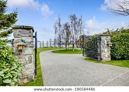 Entrance iron gates with stone columns. View of driveway and roundabout.