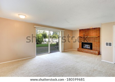 Empty living room with a brick background fireplace, carpet floor and walkout deck