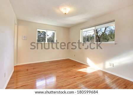 Warn colors empty room with two small windows and hardwood floor