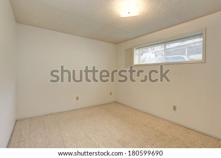 Empty small room with ivory walls and beige carpet floor. View of the  narrow window