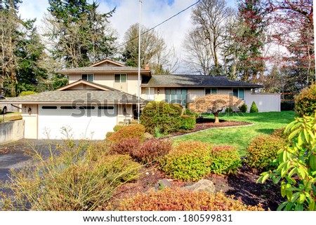 Big siding house with beautiful landscaping. View of the wet drive way and curb appeal