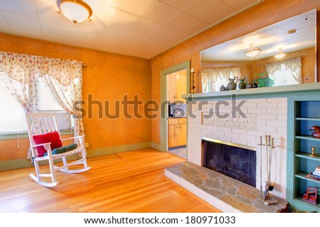 Living room corner. White rocking chair, brick background fireplace.