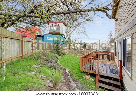 Fenced backyard with flower bed and wooden walkout deck