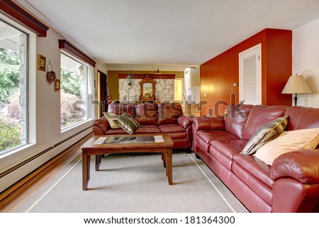 Luxury living room with stone wall trim . Furnished with burgundy leather couches and coffee table.