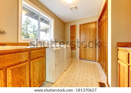 Narrow laundry room with a window. Furnished with washbasin cabinet, dryer and washer.