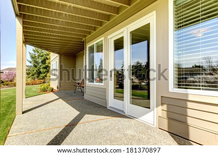 Backyard walkout deck with concrete floor. View of slide doors and windows