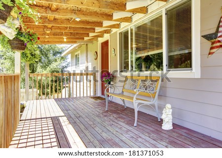 Front wooden deck with antique bench. Deck decorated with small statue and hanging flower pots