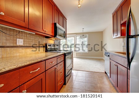 Modern kitchen interior. Cherry wooden cabinets with marble counter tops blends with steel appliances