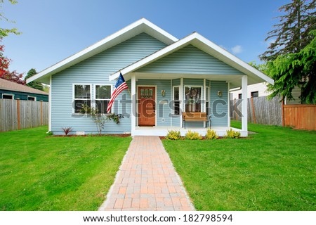 Small clapboard siding house. View of porch with bench and walkway