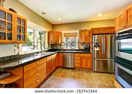 Spacious kitchen room with tile floor, wood cabinets and steel appliances