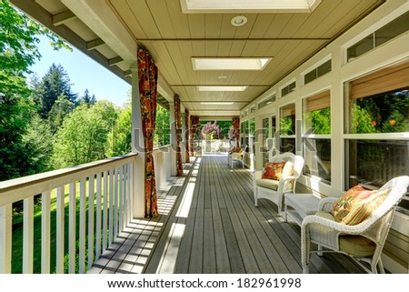 Beautiful backyard deck with white wicker chairs, table and settee. Floral curtains and pillows complete the look