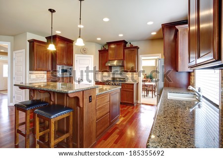 Beautiful kitchen room with oak cabinets, steel appliances. View bar counter with black chairs