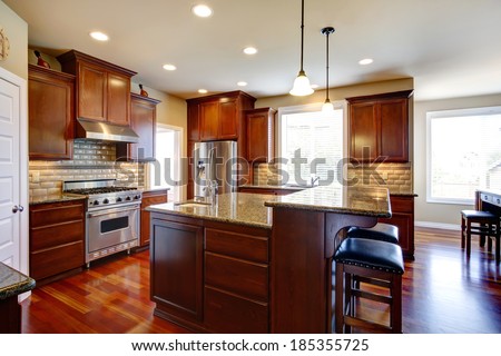 Beautiful kitchen room with oak cabinets, steel appliances. View bar counter with black chairs.