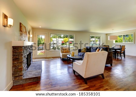 Living room with stone background fireplace, sofa, chairs and coffee table. View of entrance door and dining table set