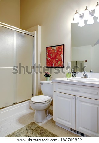 Bathroom with high ceiling. View of white vanity, toilet and bath tub with glass doors