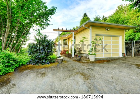 Yellow one story house with garage. View of open small gate with walkway and garage with driveway