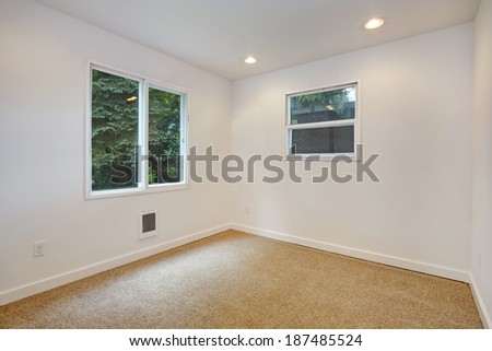 Empty small room with two windows, white walls and beige carpet floor