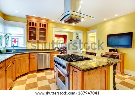 Yellow kitchen interior. View of island with built-in stove and kitchen hood above it
